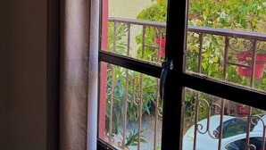 Una ventana con vistas a una montaña, un coche blanco estacionado afuera y un edificio de fachada de ladrillo.