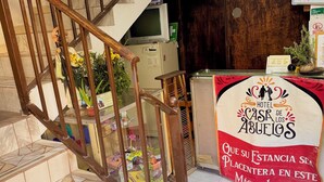 Zona de recepción de un hotel con una escalera, un mostrador de recepción y un cartel que dice 'Hotel Casa de Abuelos'.