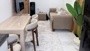 Een moderne woonkamer met een houten tafel, een beige bank en een grote groene plant.
