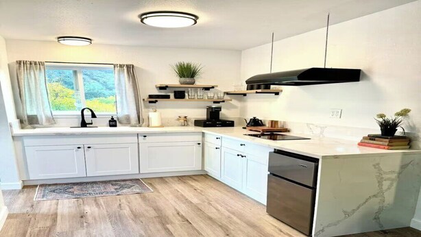 Una cocina moderna con armarios blancos, encimera de mármol y lavavajillas integrado.