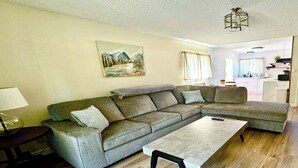Una sala de estar con un sofá modular, una mesa de centro y un cuadro en la pared.