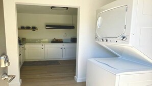 Un lavadero con lavadora y secadora, una zona de cocina con armarios y encimera, y suelo de madera.