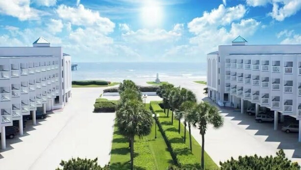 Ein modernes Hotel mit symmetrischer Gestaltung, das einen zentralen Innenhof mit Palmen und einen Blick auf den Ozean bietet.