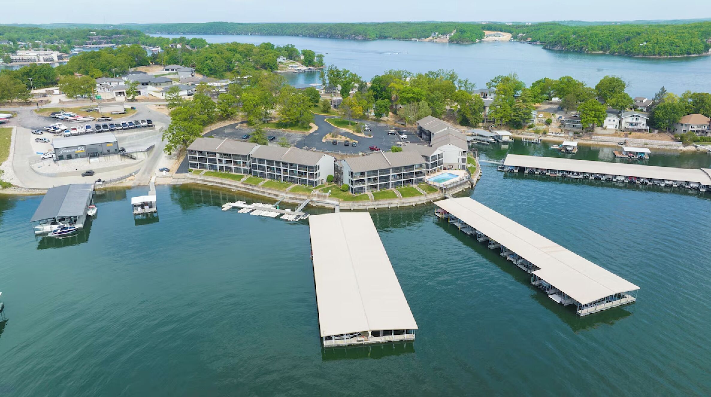 Vue aérienne d’une propriété au bord du lac, avec un grand bâtiment, plusieurs quais et des bateaux.