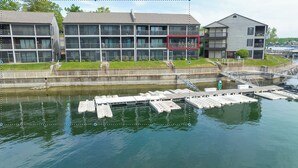A waterfront building with multiple balconies and a dock with boats. - Beautifully Updated Lakefront Condo – Cozy, Quiet, and Close to the Action! (Osage Beach)