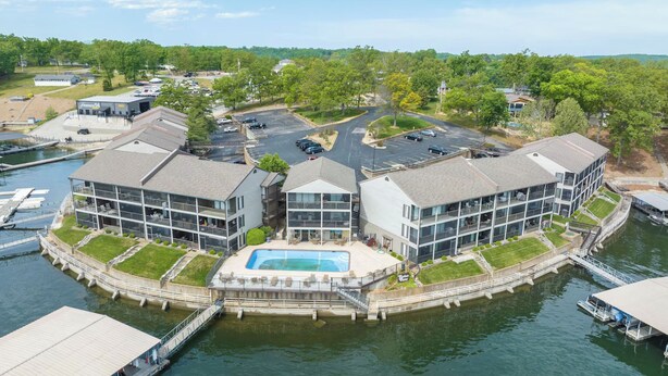 A waterfront hotel with a central pool, multiple buildings, and a parking area. - Beautifully Updated Lakefront Condo – Cozy, Quiet, and Close to the Action! (Osage Beach)
