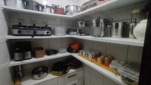 A kitchen with shelves holding pots, pans, and cooking utensils.