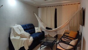 A cozy living room with a blue sofa, a white canopy bed, a small table, and two chairs.