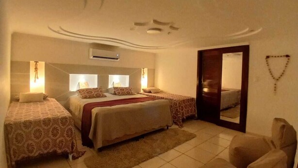 A bedroom with two beds, a large mirror, and a door leading to another room.