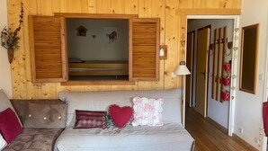 Interior acogedor de una cabaña con sofá, banca y techo de madera.