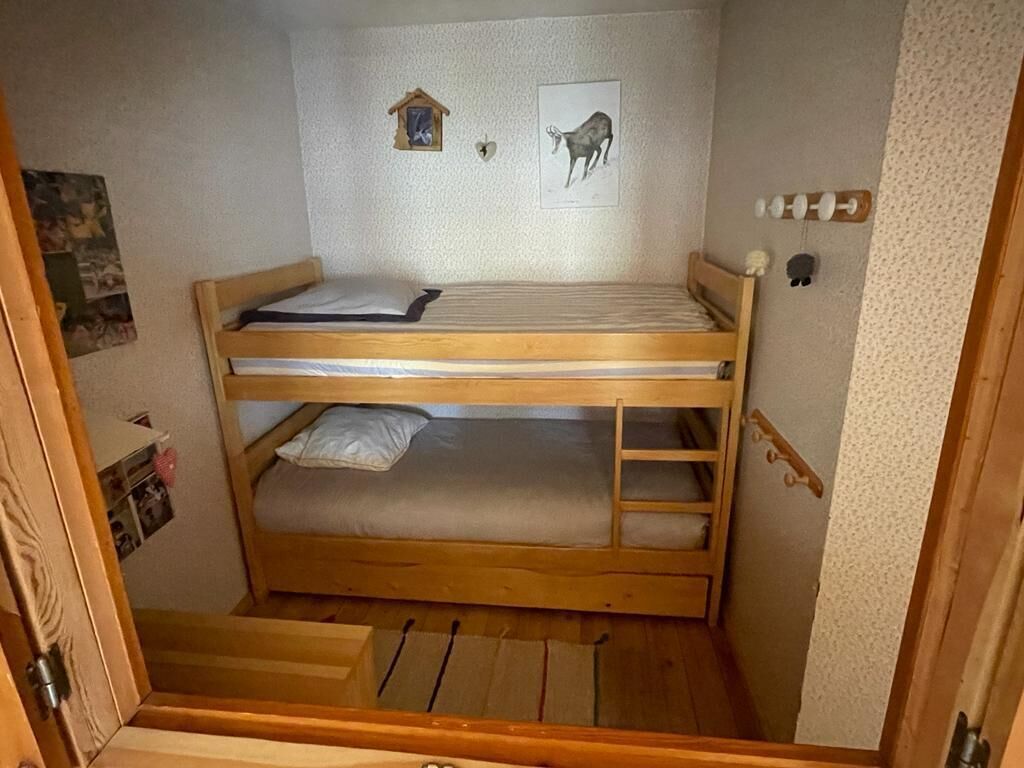 Ein Schlafraum mit Etagenbetten, einem Holzrahmen, zwei Betten, einer Treppe und einem kleinen Regal.