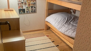 Una habitación pequeña y acogedora con literas, un escritorio con lámpara y una pared decorada con fotografías.