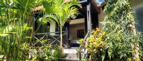 Un espacio al aire libre cubierto con escaleras que conducen a un edificio, rodeado de abundante vegetación.
