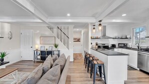A spacious living room with a large sofa and a dining area with a kitchen island. - Lakefront: Hot Tub + Fire Pit + Game Room + Pool (Tobyhanna)