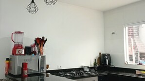 A modern kitchen with a central island, black countertops, and red bar stools. - Very beachy (Praia Grande)