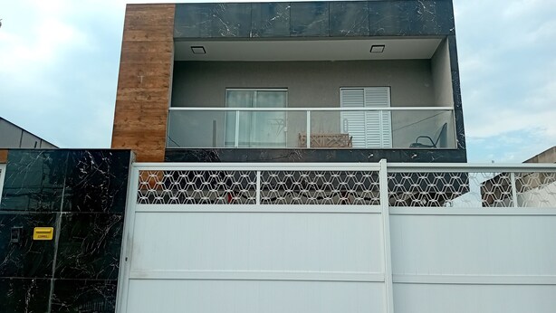 A modern two-story house with a garage door, a balcony with a railing, and a patterned floor.