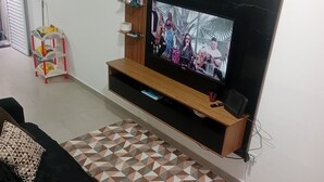 A living room with a TV on a wooden stand, a patterned rug, and a black sofa.