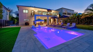 Una casa moderna con piscina, mobiliario exterior y un césped bien cuidado.