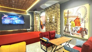 Un espace détente moderne avec un canapé rouge, une table basse en bois et une grande fresque représentant la Tour Eiffel.