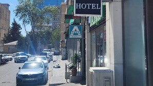Une enseigne d’hôtel indiquant « KHATAI HOTEL », avec une vue dégagée sur la façade de l’immeuble et les voitures garées le long de la rue.