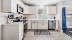 Une cuisine moderne avec des meubles blancs, un four à micro-ondes, une cuisinière et un lave-vaisselle.