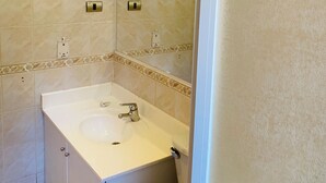 Un baño con lavamanos blanco, espejo y ducha.
