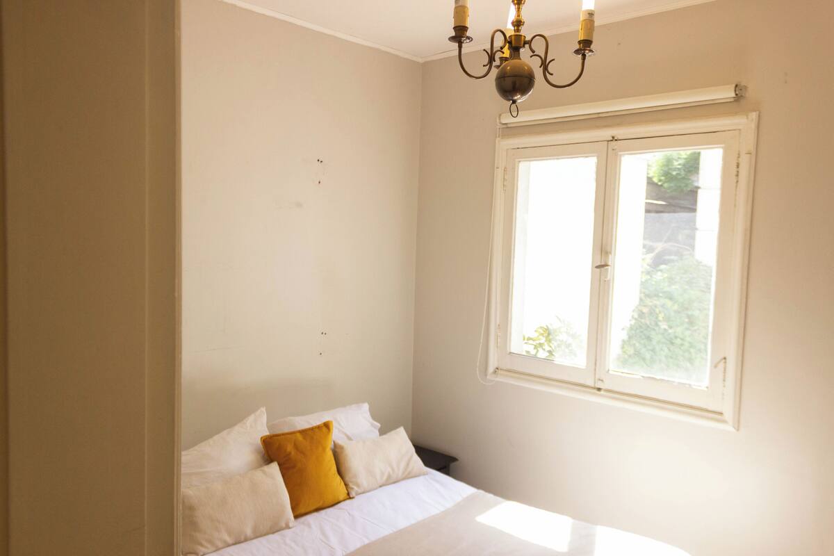 Een slaapkamer met een bed, een raam en een kroonluchter.