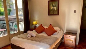 Una cama bien hecha con almohadas, una lámpara de noche y una mesita de noche de madera.