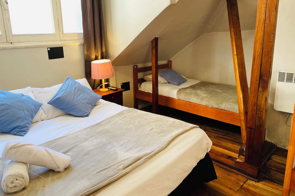 Een slaapkamer met twee bedden, een nachtkastje met een lamp en een raam met gordijnen.