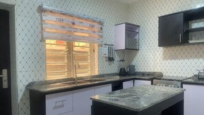 A kitchen with a countertop, sink, cabinets, and a window with blinds. - Muniz Global Apartments  (Lagos)