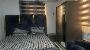 A bedroom with a bed, a wardrobe, and a seating area. - Muniz Global Apartments  (Lagos)