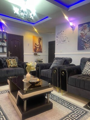 A modern living room with a black sofa set, a glass coffee table, and a decorative vase. - Muniz Global Apartments (Lagos)