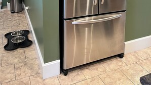 A stainless steel refrigerator in a kitchen with green walls and a tiled floor. - You'll love your stay at the Bohemian Bungalow centrally located in Terre Haute! (Terre Haute)