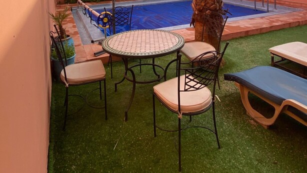 Un espace piscine agrémenté d’un palmier, d’une petite piscine et d’une table avec des chaises.