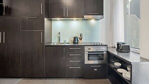 Una cocina moderna con armarios de madera oscura, electrodomésticos de acero inoxidable y una ventana con vista a la ciudad.
