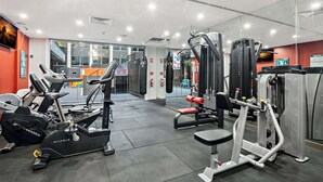 Un gimnasio con máquinas de cardio, equipo de levantamiento de pesas y un espejo grande.