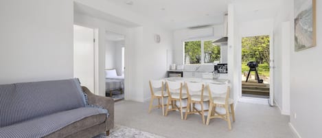 A modern interior with a sofa, dining table, chairs, and a kitchen area.