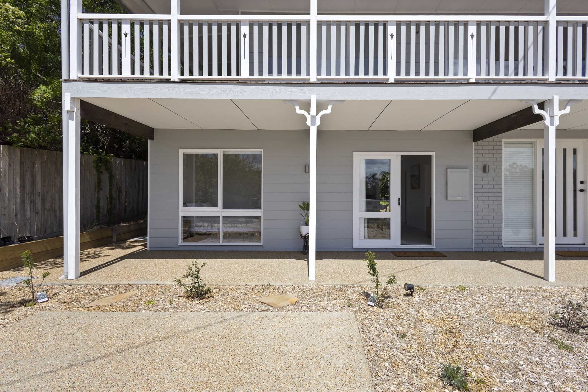 A two-story building with a covered patio, large windows, and a door leading to an interior space.