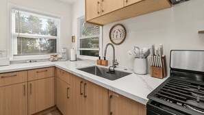 A modern kitchen with wooden cabinets, a stainless steel sink, and a built-in stove.