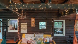 A cozy cabin interior with a sofa, hanging lights, and a wooden wall.