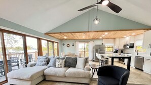 A modern living room with a sectional sofa, a dining area, and a kitchen. - Serene 2-bedroom lake house (Rutledge)