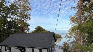 A house with a dark roof, a porch, and a view of a body of water. - Serene 2-bedroom lake house (Rutledge)