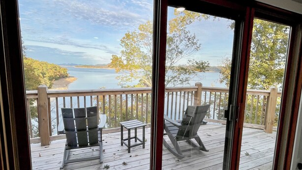 A deck with two chairs and a small table, overlooking a body of water and trees. - Serene 2-bedroom lake house (Rutledge)