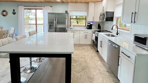 A modern kitchen with white cabinets, a central island, and a wooden ceiling. - Serene 2-bedroom lake house (Rutledge)