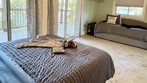 A bedroom with a bed, a ceiling fan, a window with curtains, a sofa, and a television on the wall. - Serene 2-bedroom lake house (Rutledge)
