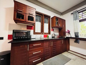 A kitchen with wooden cabinets, a microwave, and a sink. - Hidden Gem - Goyambokka (Tangalle)