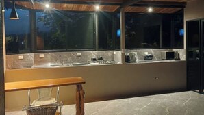Eine moderne Küche mit Marmorarbeitsplatte, Holzbalkendecke und einem großen Fenster.