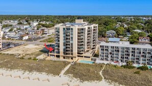 A multi-story hotel with balconies, a swimming pool, and a beach view. - Beachfront Breeze @ Sea Castle North Myrtle Beach (North Myrtle Beach)