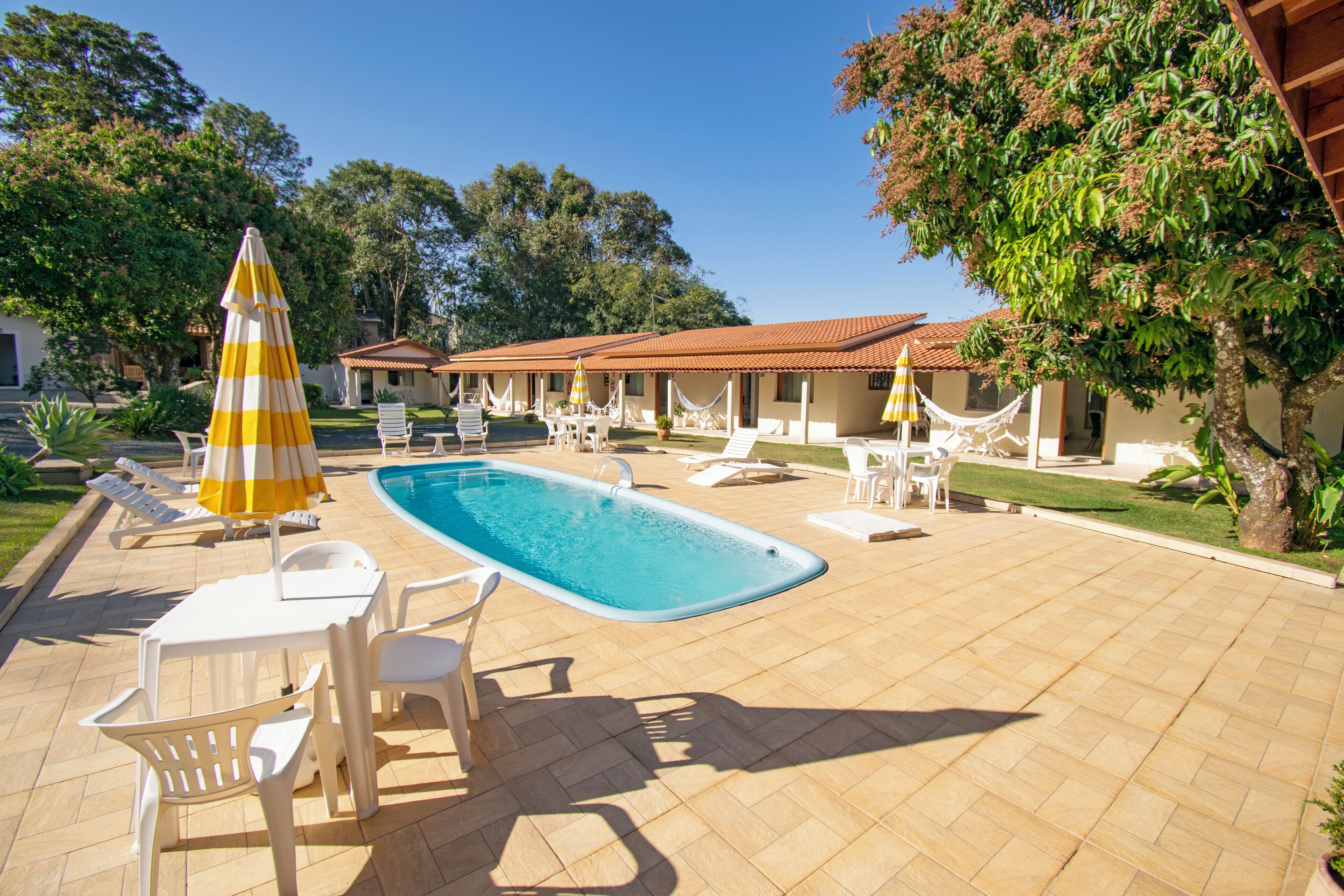 Uma área de piscina com espreguiçadeiras, mesa e guarda-sóis.