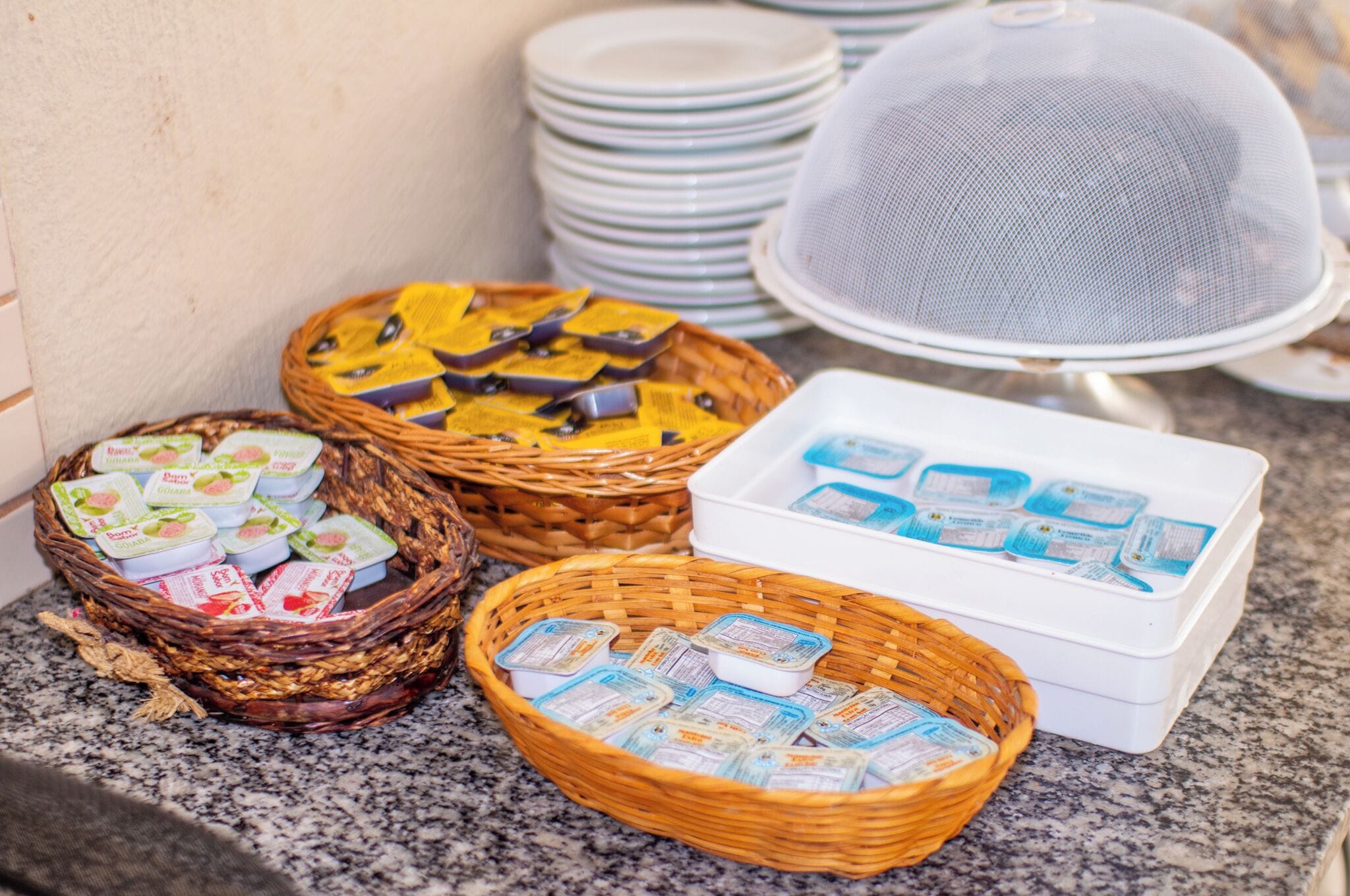 Una mesa de buffet con diversos alimentos en cestas y recipientes, incluyendo yogur y otros productos envasados.